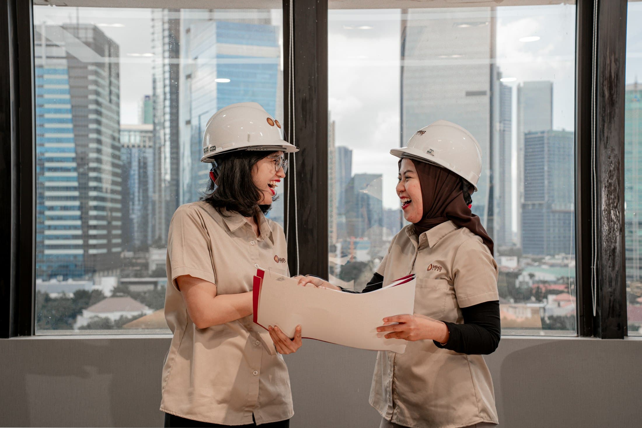 Two engineers in hard hats reviewing documents